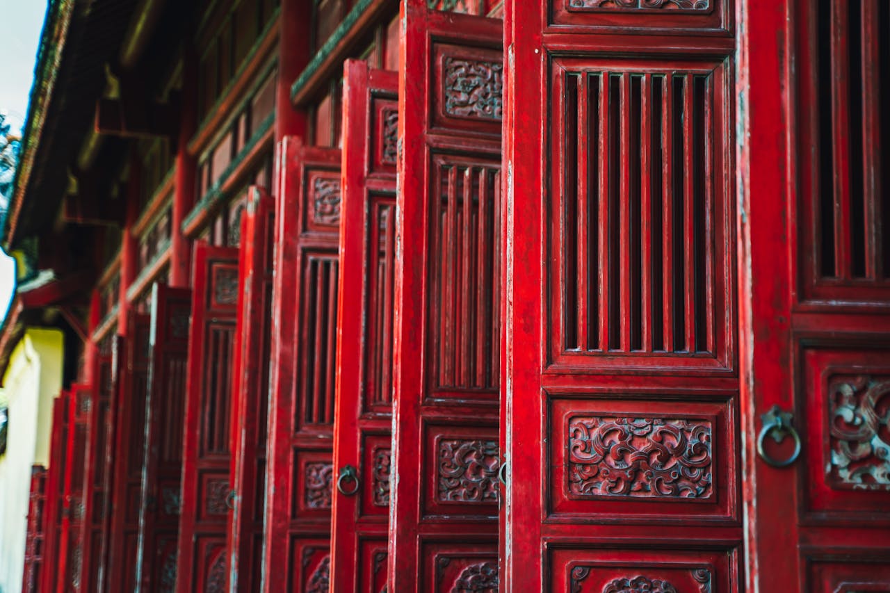 gallery-6 Intricately carved red wooden doors in Huế, Vietnam showcasing traditional design.