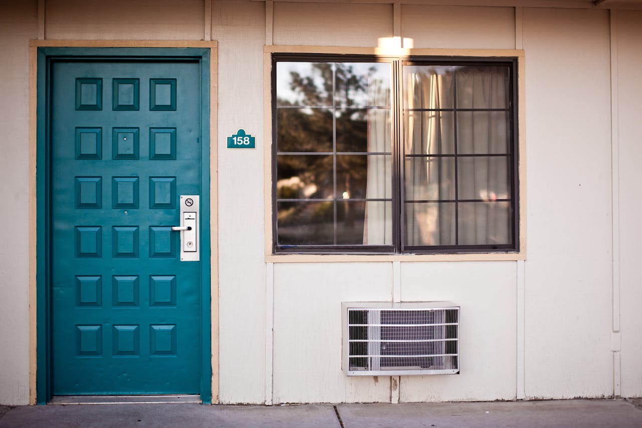 hero-img-01 Front view of a teal door and window, typical motel exterior entrance facade.