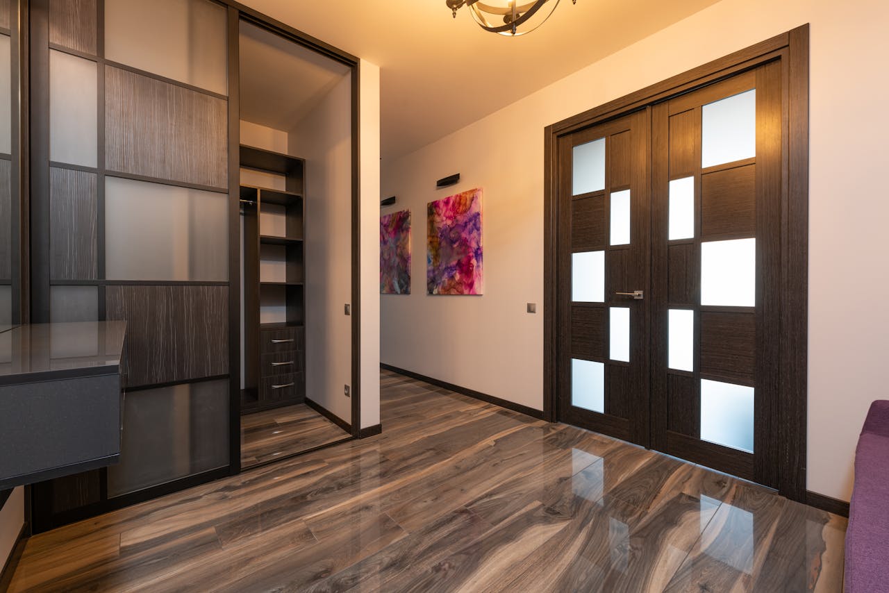 hero-img-02 Spacious modern hallway featuring wooden doors, a sliding closet, and abstract art for a contemporary look.
